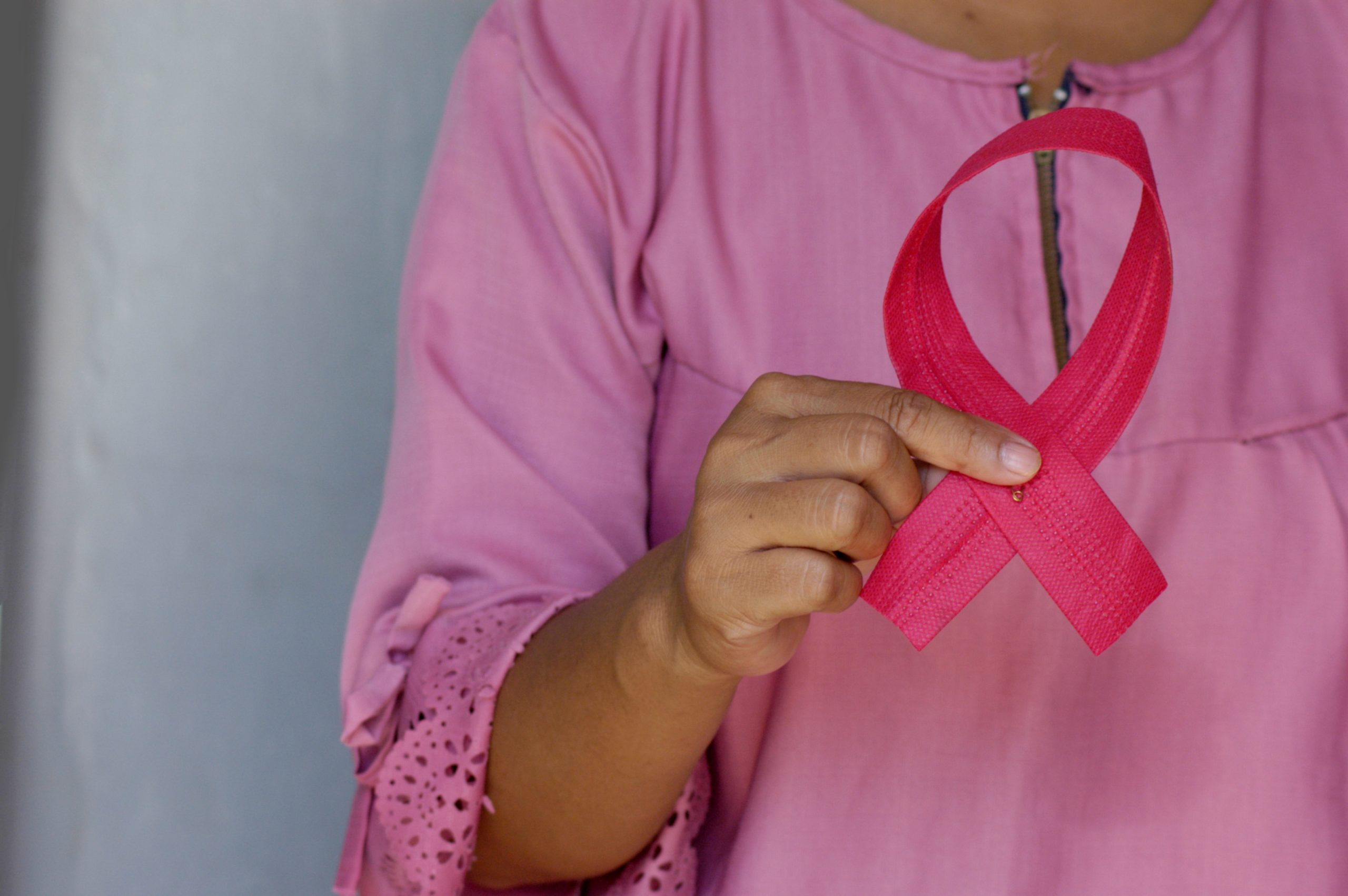 woman holding breast cancer ribbon for risk factors for breast cancer